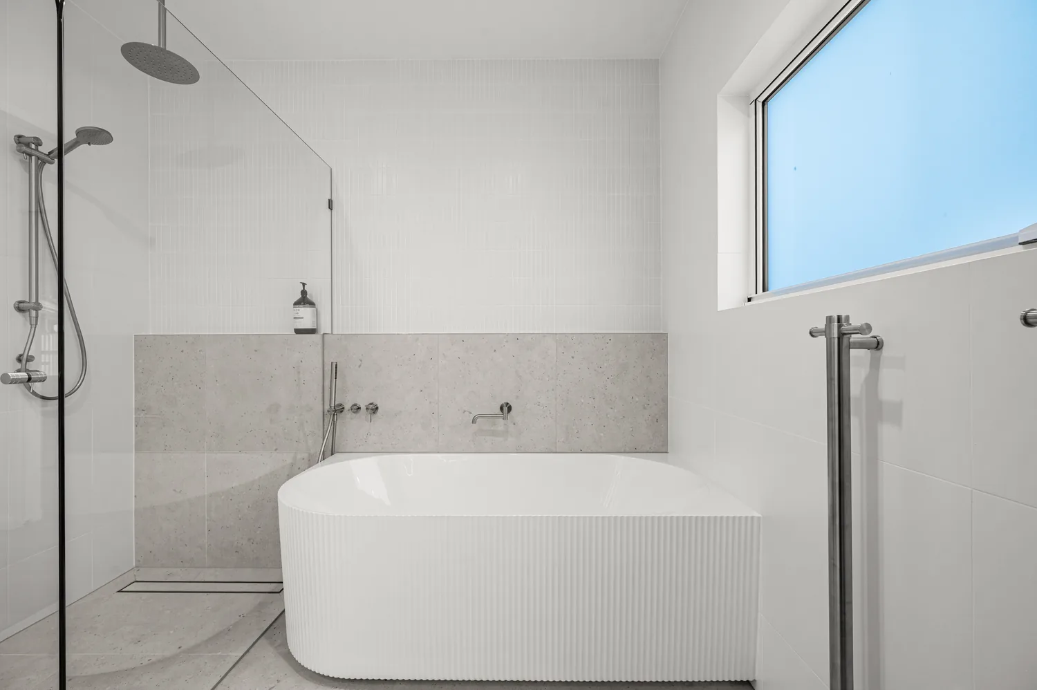Fluted freestanding bath with walk-in shower and grey tiling