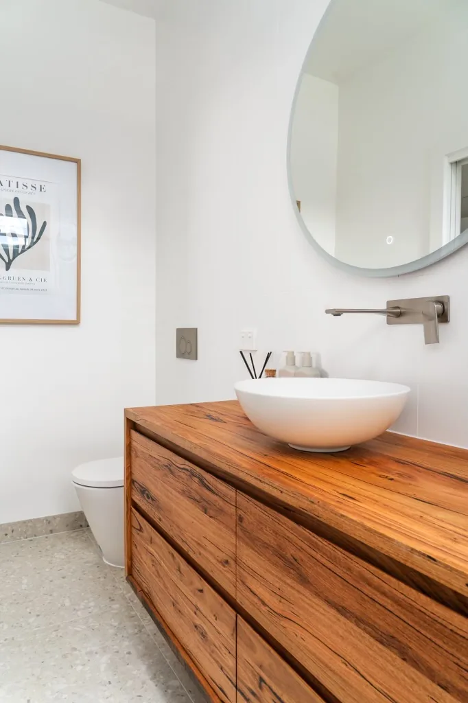 Timber vanity with vessel basin and round mirror