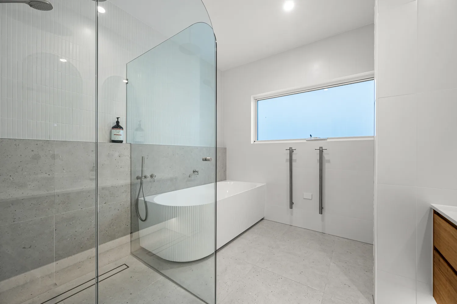 Ensuite with curved freestanding bath and frameless glass shower