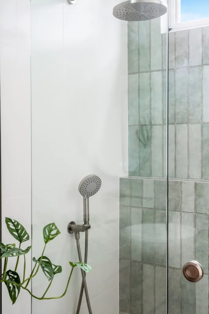Walk-in shower with green vertical feature tiling and rain head